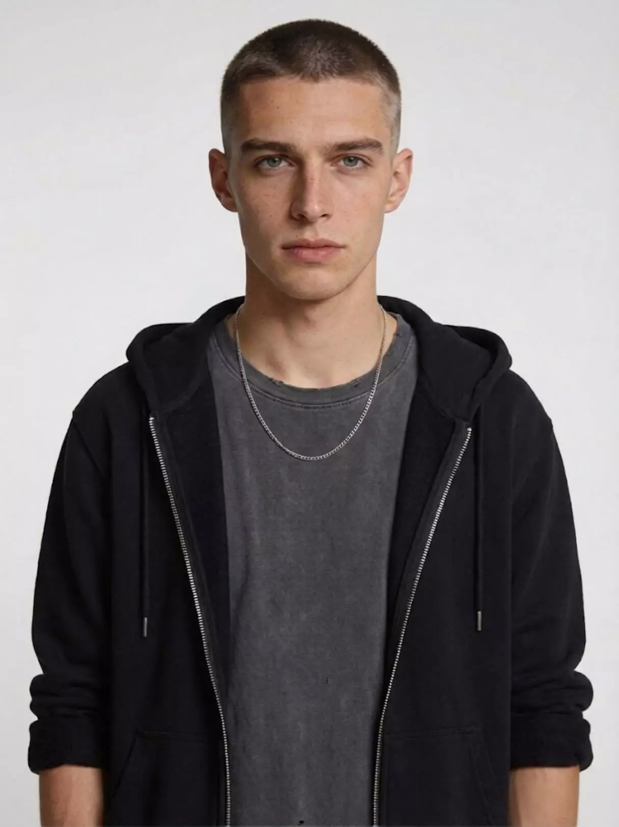Man with long oblong face and low-to-mid fade buzz cut, #5 top length adding width and balance, neutral studio background.