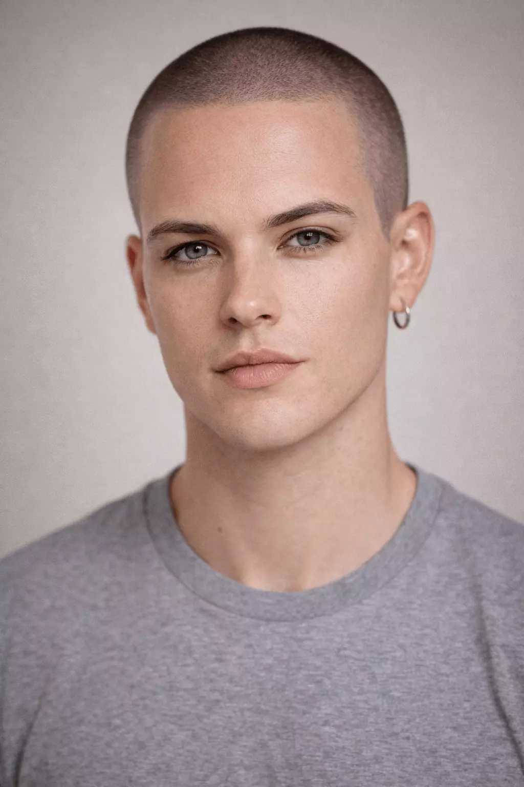 Man with an oval face rocking a #1 induction buzz cut, symmetrical features, minimalist studio background, 8k photography.
