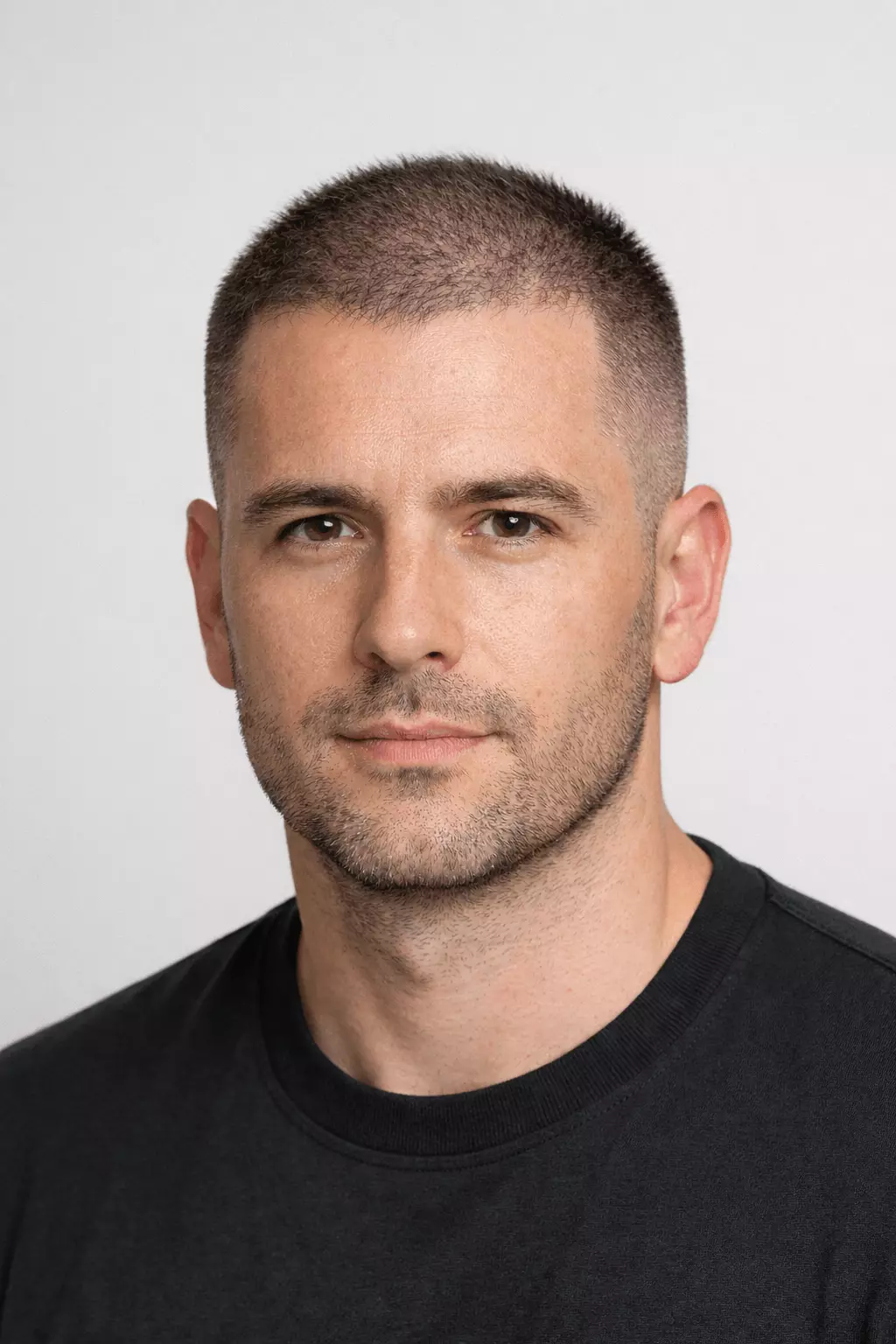 Man with thinning hair wearing crew transition buzz, textured top, fade sides, modern hairstyle.