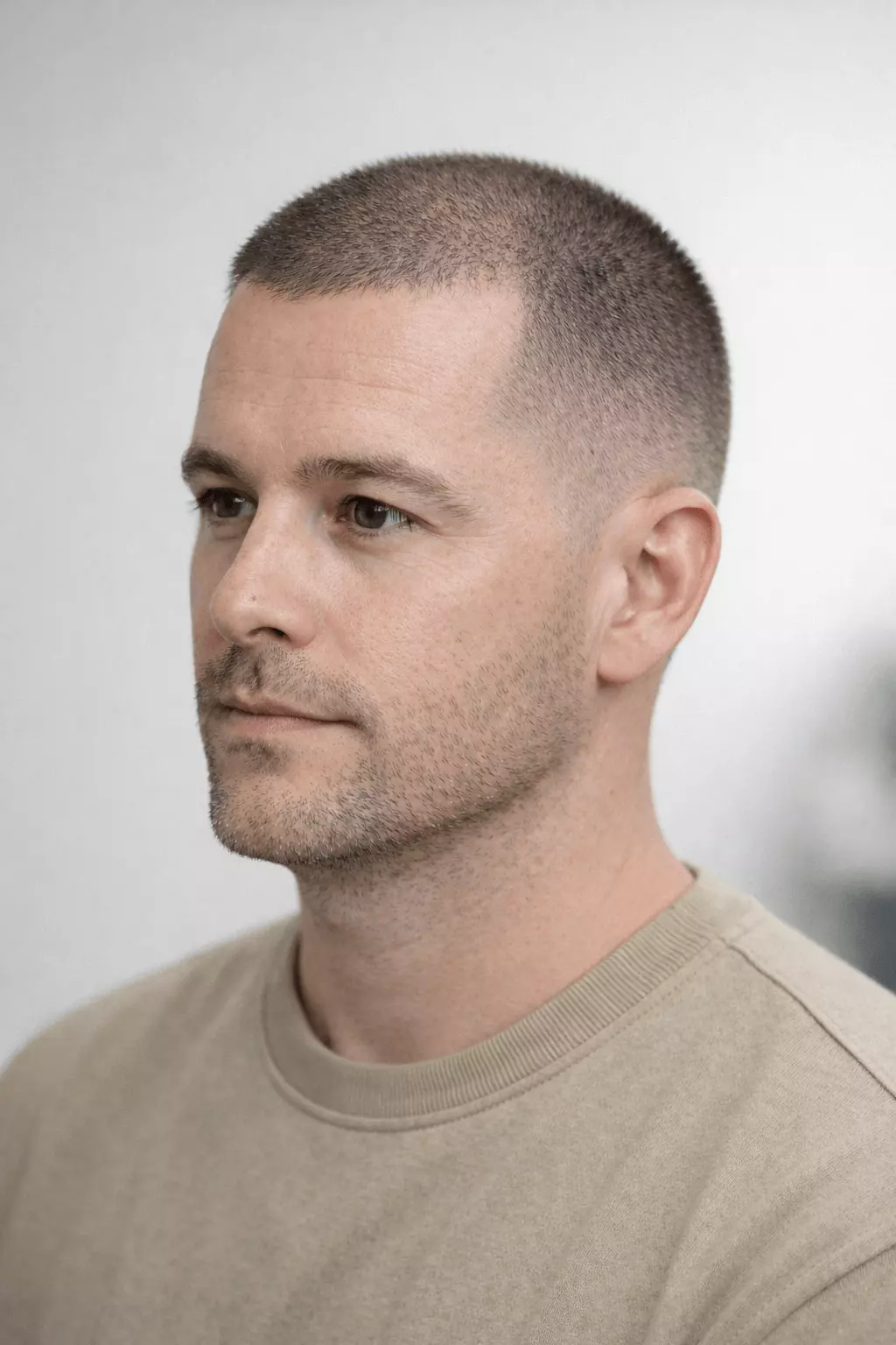 Man with thinning hair wearing mid-fade buzz cut, smooth transition from top to sides, urban background.