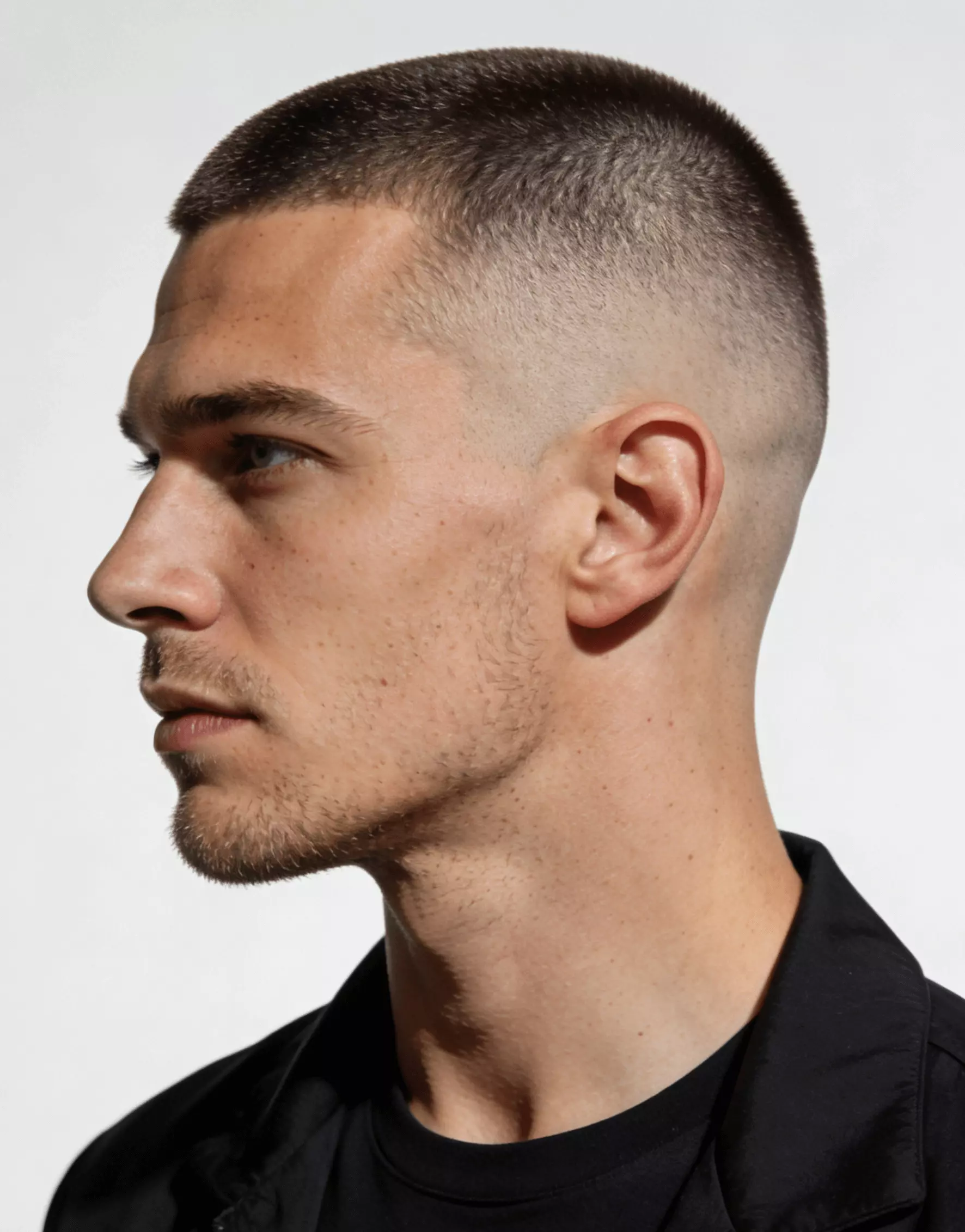 Skin fade buzz cut with #1–#2 top, ultra-clean sides, bold masculine appearance.