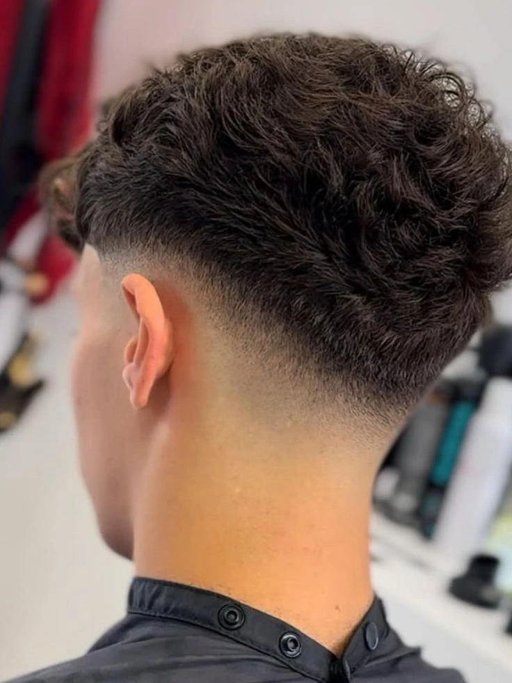 A man with a low fade haircut, showing a gradual taper starting just above the ears.