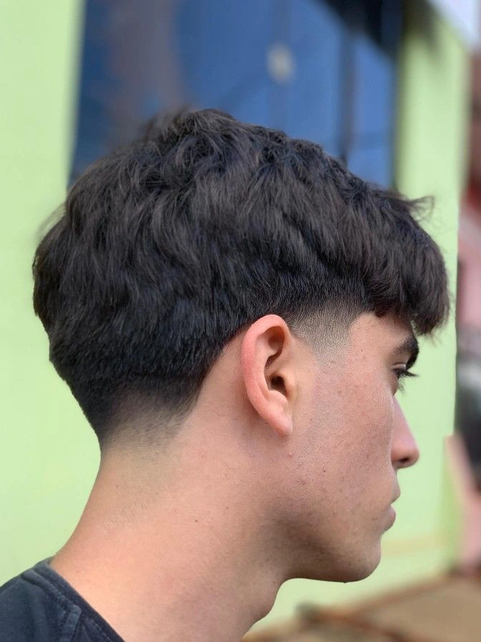 Classic low taper fade on oval face with medium-length textured top hair